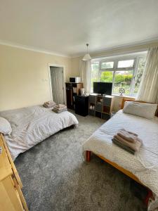 1 dormitorio con 2 camas, escritorio y TV en White Wings, en Nuneaton
