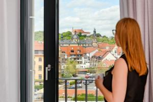 Eine Frau, die aus dem Fenster schaut auf eine Stadt in der Unterkunft Holiday Inn Express - Fulda, an IHG Hotel in Fulda