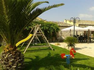 a playground with a slide in a yard with a palm tree at Oasi Di Cava Ispica in Pietre Nere San Zagaria