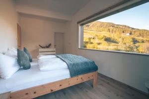 een slaapkamer met een bed en een groot raam bij Landart-Appartements in Virgen