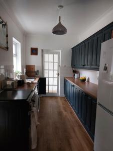 a kitchen with black cabinets and a white refrigerator at AROHA in Glastonbury