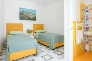 two beds in a room with yellow and green at Angolo di Paradiso Sorrento Coast in Moiano