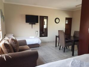 a hotel room with a couch and a table and a bed at Private Apartments & Biz Stays Pretoria in Pretoria