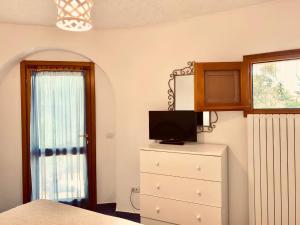 a bedroom with a dresser with a tv and a window at Appartamento Vasiliki in Porto San Paolo