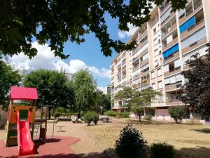 a playground in a park in front of a building at Résidence du Parc fleuri de Lyon Cœur Lyon8 PKG free 95m2 in Lyon