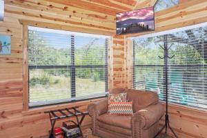 a living room with a couch and two large windows at Arbor House of Dripping Springs - Finch House in Dripping Springs