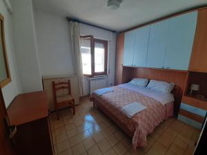 APPARTAMENTO ISIDE fronte spiaggia في فوساتشيزيا: غرفة نوم بسرير وكرسي ونافذة