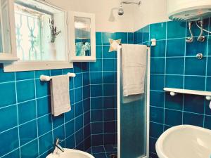 a blue tiled bathroom with a sink and a toilet at Pinelopi Room in Olbia