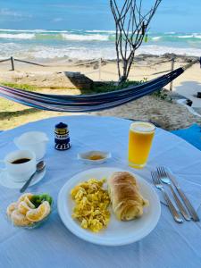 una mesa con un plato de huevos revueltos y pan en la playa en Hostal Galapagos by Bar de Beto, en Puerto Villamil