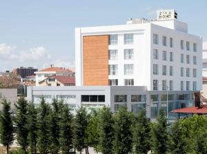 ein großes weißes Gebäude mit Bäumen davor in der Unterkunft Zin D Home Otel Alemdağ in Istanbul