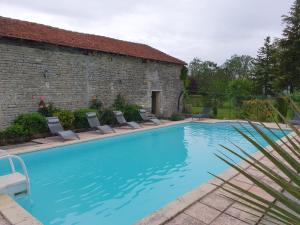 a large swimming pool with chairs and a building at La Fontenelle Meublé T2 in Sainte-Sévère