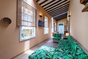 a large green couch in a room with windows at Casona Gildana: Historia, Patrimonio/E-working in Arucas