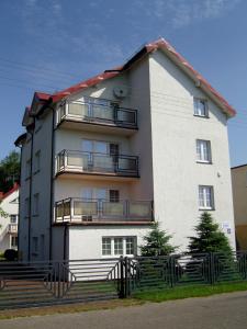 Un grand bâtiment blanc avec des escaliers se trouve juste devant. dans l'établissement Pokoje Gościnne - Leśna 8, à Ustronie Morskie