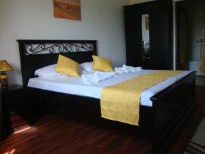 a black bed with yellow pillows in a room at Casa Lacul Sarat in Techirghiol