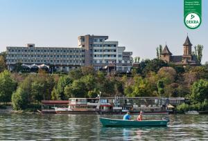 dos personas en un barco en un río con edificios en Faleza Hotel by Vega, en Galaţi