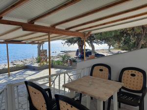 einen Holztisch und Stühle auf einem Balkon mit Meerblick in der Unterkunft Paraga Rooms Pefkari in Pefkari