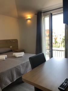 Habitación con cama, mesa y ventana en Affittacamere Su Caboni, en Tortolì