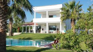 a house with a swimming pool and palm trees at ALASHATO Alacati in Alacati