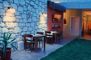 a patio with tables and chairs next to a stone wall at Rijeka Alaçatı in Çeşme