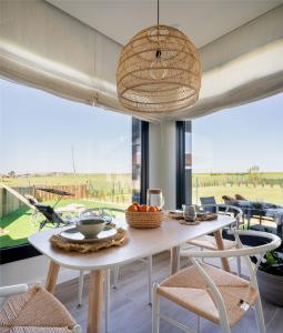 une salle à manger avec une table, des chaises et une grande fenêtre dans l'établissement OCEANSUITESLANGRE, à Galizano