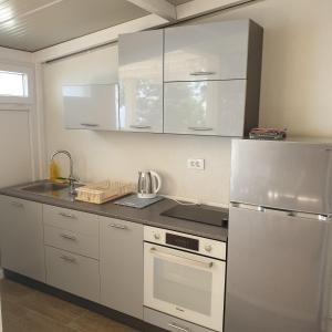 cocina con armarios blancos y nevera de acero inoxidable en Apartments Rašica, en Molunat
