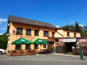 a restaurant with a green umbrella in front of a building at Rodinný pension U Soudku in Rudník