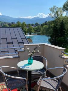 a table with chairs and a vase of flowers on a balcony at Apartman River Una in Bihać