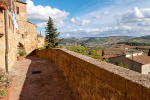 a stone wall with a view of the hills at Camere Gozzante in Pienza