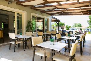um restaurante com mesas, cadeiras e janelas em Irilena Hotel em Lassi