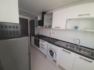 a kitchen with white cabinets and a washer and dryer at Un appartement de charme à Hammamet in Hammamet