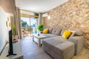 sala de estar con sofá y pared de piedra en 2BD-Piscina-Playa-Port Aventura2 en Salou