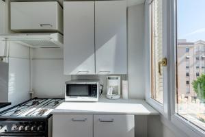 d'une cuisine avec des placards blancs, un four micro-ondes et une fenêtre. dans l'établissement Annecy Triangle d'Or - 3 bedroom apartment, à Annecy
