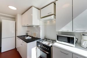 La cuisine est équipée de placards blancs et d'un four avec plaques de cuisson. dans l'établissement Annecy Triangle d'Or - 3 bedroom apartment, à Annecy
