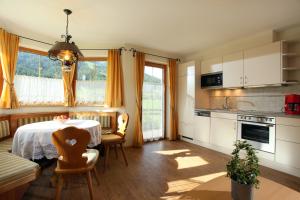 une cuisine avec une table et des chaises et une cuisine avec une fenêtre dans l'établissement Haus Hirzinger, à Brixen im Thale