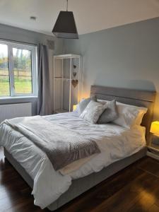 1 dormitorio con 1 cama blanca grande y ventana en The Grove, en Belturbet