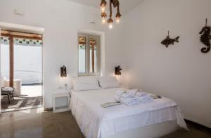 a white bedroom with a bed with towels on it at Geomilos Deluxe Rooms in Triovasálos