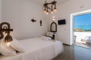 a white bedroom with a bed and a view of the ocean at Geomilos Deluxe Rooms in Triovasálos