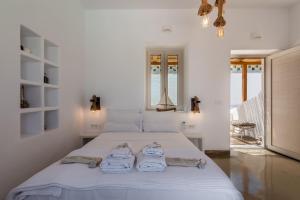 a white bedroom with a bed with towels on it at Geomilos Deluxe Rooms in Triovasálos