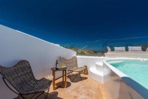 a patio with two chairs and a swimming pool at Geomilos Deluxe Rooms in Triovasálos