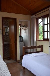 a bedroom with a bed and a kitchen with a window at Chale Ideal in Conceição da Ibitipoca