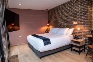 1 dormitorio con 1 cama grande y pared de ladrillo en Casa Rosé Hotel en Carmen de Viboral