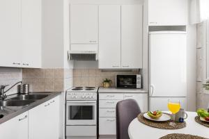 a kitchen with white cabinets and a table with a plate of food at Apartments Borg Dyyni in Pori