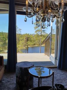 een woonkamer met een kroonluchter en een groot raam bij Solhytta Fantastisk beliggenhet! Hytte til leie på Skrim! in Kongsberg