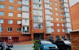 aartment building with cars parked in front of it at Апартаменты ПРЕМЬЕР in Kamianets-Podilskyi