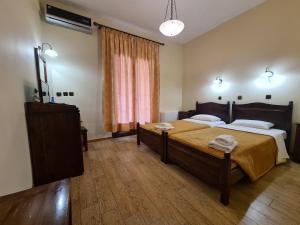 a bedroom with two beds and a dresser and a window at Agnanti Hotel in Velventós