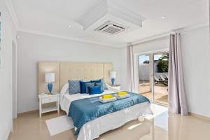 - une chambre blanche avec un lit et des oreillers bleus dans l'établissement Villa Pianda by Villa Plus, à Almancil 14 autres photos