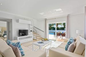 d'un salon avec un mobilier blanc et une vue sur l'océan. dans l'établissement Villa Pianda by Villa Plus, à Almancil