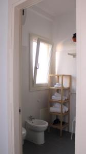 een witte badkamer met een toilet en een raam bij TerreAmare Agriturismo in Porto Cesareo
