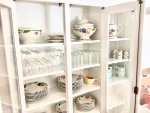 a white cabinet filled with plates and dishes at Résidence Alpha Centauri in Carcassonne