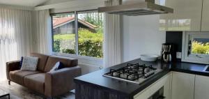 a kitchen with a stove top oven next to a couch at Diek42 in Kattendijke +17 photos